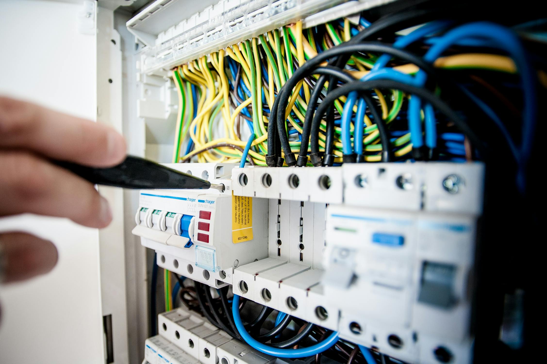 Electrician working on electrical panel switchboard with circuit breakers